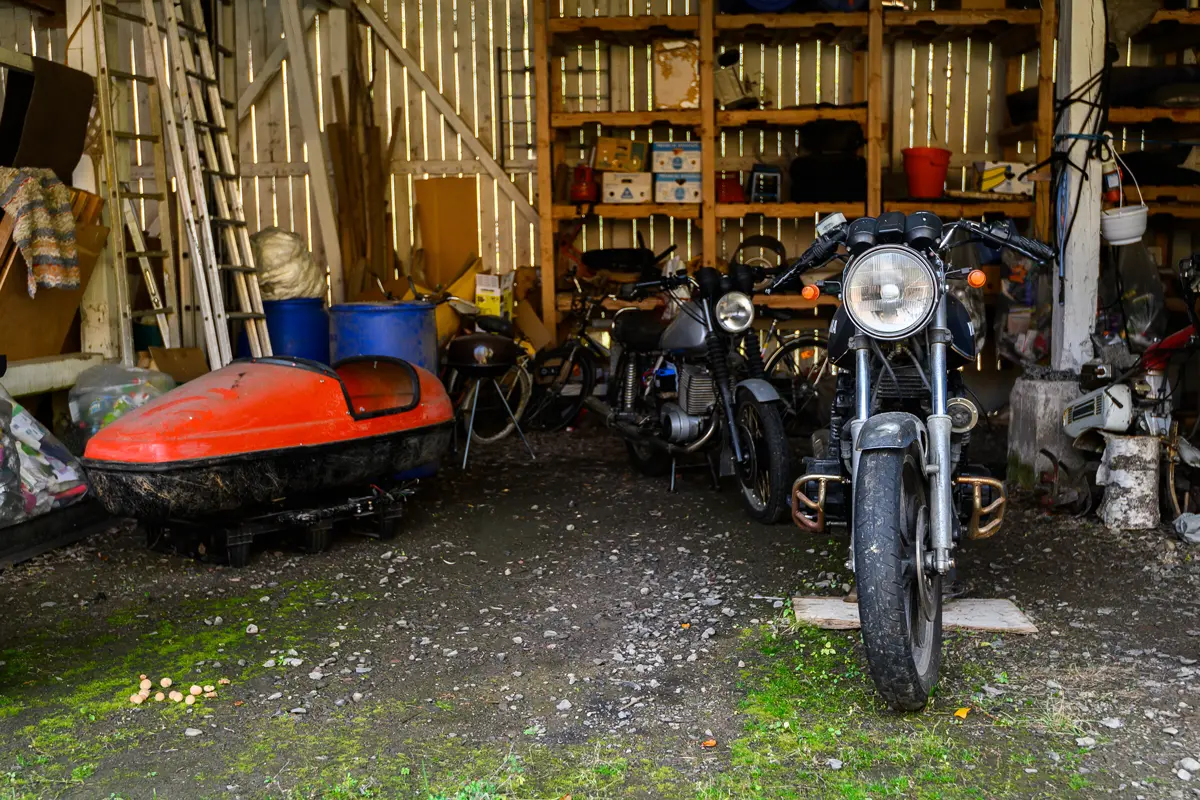 Vollgestellte Garage mit Werkzeug und Motorrad vor der Garagenentrümpelung in Leipzig